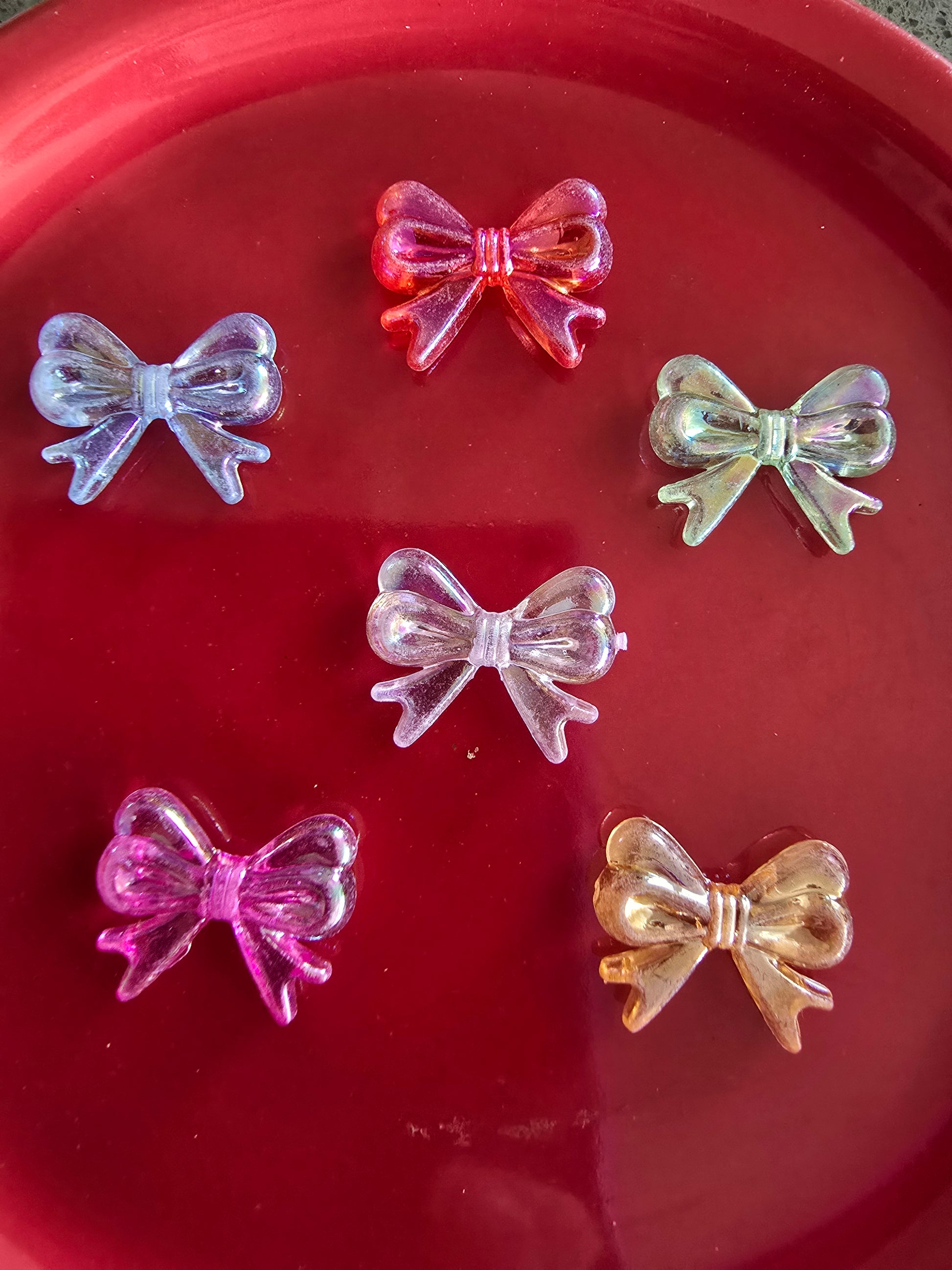 Variedad de moños translúcidos de acrílico en colores vibrantes sobre plato rojo