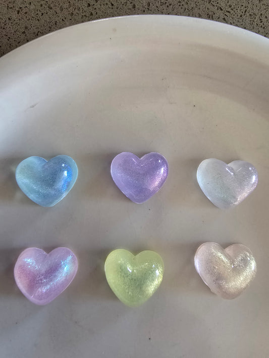 Variedad de corazones nacarados translúcidos de resina en colores pastel sobre plato blanco