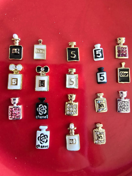 Set de 10 mini perfumes decorativos estilo lujo inspirados en marcas como Chanel y DSet de 10 mini perfumes decorativos estilo lujo inspirados en marcas como Chanel y Dior, con diseños en negro, blanco, dorado y plateado sobre fondo rojo, ideales para nail art y manualidades premium 