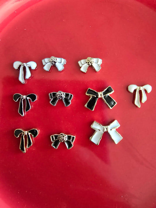 Set de 10 lazos decorativos elegantes en blanco y negro con detalles dorados sobre fondo rojo, perfectos para nail art y manualidades premium 